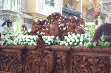 Close up of the flowers & wood carving of the paso, with a view of spectators looking on from their balcony.